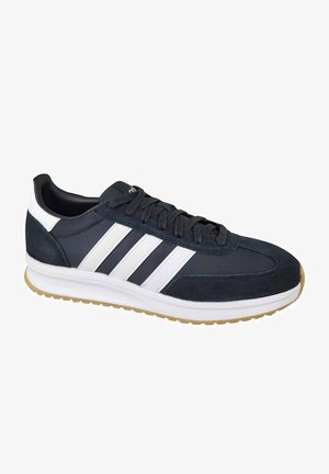 Zapatillas de ante y tela azul oscuro con rayas blancas, suela de goma y cordones negros. Presenta una puntera redondeada y un forro suave.
