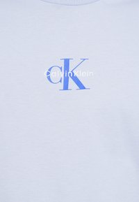 Ανοιχτό μπλε βαμβακερό T-shirt με κοντά μανίκια που έχει μεγάλο μπλε λογότυπο "CK" και το κείμενο "CalvinKlein" σε λευκό από κάτω.