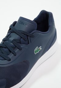 Navy modré sportovní boty s vrškem z mesh a syntetického materiálu, bílou podrážkou, plochými šňůrkami a zeleným krokodýlem na boku.