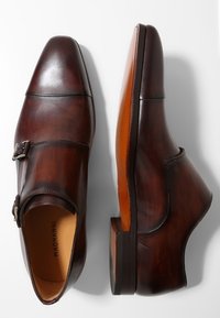 Chaussures en cuir brun avec un bout arrondi, une seule boucle et une texture lisse. Dotées d'une finition polie et d'une semelle robuste.