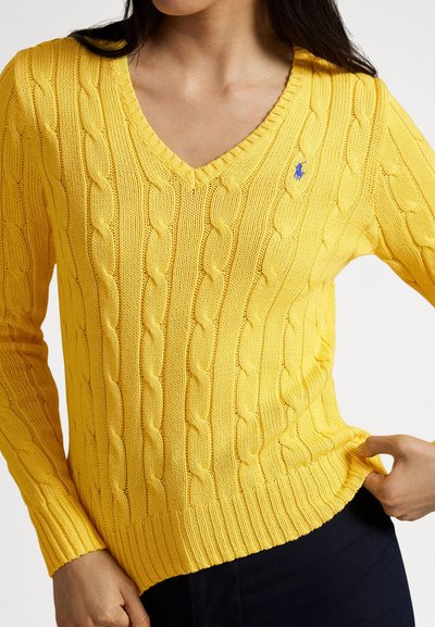 Κίτρινο πλεκτό πουλόβερ με V-λαιμόκοψη, διακοσμημένο με σχέδια κόμπων και ριμπ μανσέτες. Μικρό λογότυπο στο αριστερό στήθος. Μαλακή υφή.