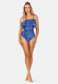 Niebieski jednoczęściowy strój kąpielowy z falbaną na górze, geometrycznymi wzorami, regulowanymi ramiączkami i wysokim krojem nogawki.