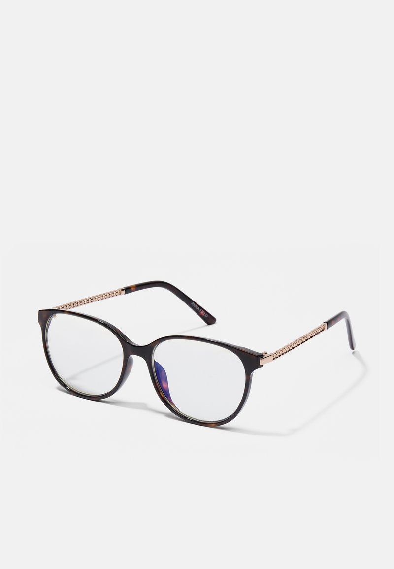 Καφέ καππαδοκικά γυαλιά ηλίου με ωοειδή φακούς, χρυσό τονισμένο διακοσμητικό στις βραχίονες και σχέδιο από μέταλλο στα χέρια.