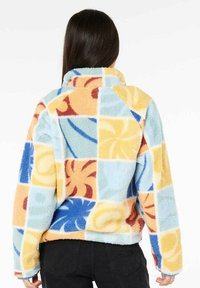 Pullover in pile con un design patchwork composto da quadrati pastello, motivi floreali in arancione, blu e giallo, colletto alto e vestibilità comoda.