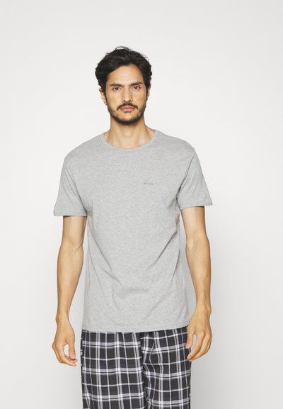 Camiseta de algodón gris con cuello redondo, mangas cortas y un pequeño logotipo impreso en el pecho, combinada con pantalones de pijama de cuadros en blanco y negro.