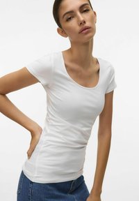 T-shirt bianca aderente con scollo a barco e maniche corte, realizzata in tessuto morbido, che abbraccia il corpo con una texture sottile e dettagli minimi.