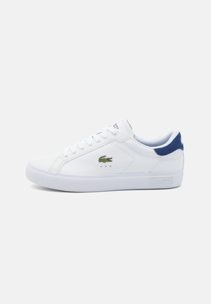 Białe syntetyczne sneakersy o gładkiej fakturze, niebieskie akcenty na pięcie oraz zielone haftowane logo krokodyla po boku.