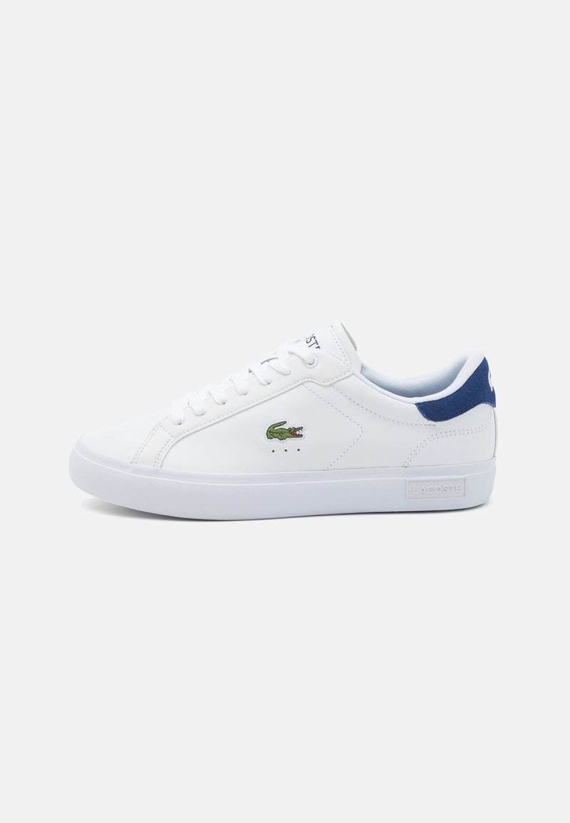 Zapatillas sintéticas blancas con textura suave, acentos azules en el talón y un logo de cocodrilo bordado en verde en el lateral.