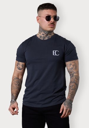 Navy blue crew-neck t-shirt made of smooth fabric, featuring a white logo on the left chest area. Fitted design with short sleeves.