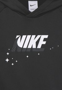 Czarna bluza z kapturem z wyraźnym bia�łym logo "NIKE" z efektem gradientu, otoczona akcentami w kształcie gwiazdek, wykonana z materiału Therma-FIT.