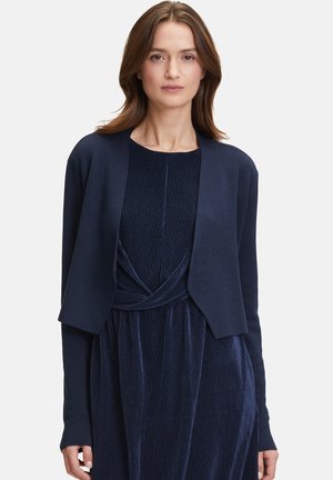 Marineblauer Strickcardigan aus weichem Material mit offenem Frontdesign und langen Ärmeln, getragen über einem passendem, strukturierten Kleid.