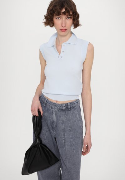 Lichtblauw mouwloos polo-shirt met een kraag en knoopsluiting, gecombineerd met grijze hoge taillebroeken en een zwarte leren handtas.