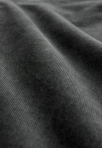 Suur lähedalt tumehall kude, millel on peened sooned ja pehmed voldid, luues õrnu varjusid.