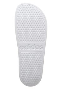 Bílá gumová stélka s texturovaným povrchem a malými vyvýšenými trojúhelníky, embosované logo "adidas" na spodní straně.