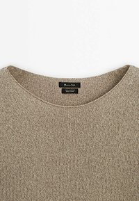 Pull beige en coton tricoté avec col rond et étiquette noire indiquant "Massimo Dutti 100% coton, fabriqué en Chine."