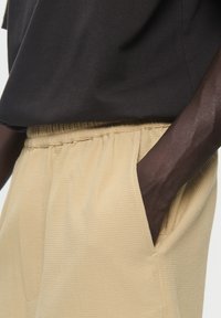 Black short-sleeve shirt paired with beige textured shorts featuring an elastic waistband and side pockets.