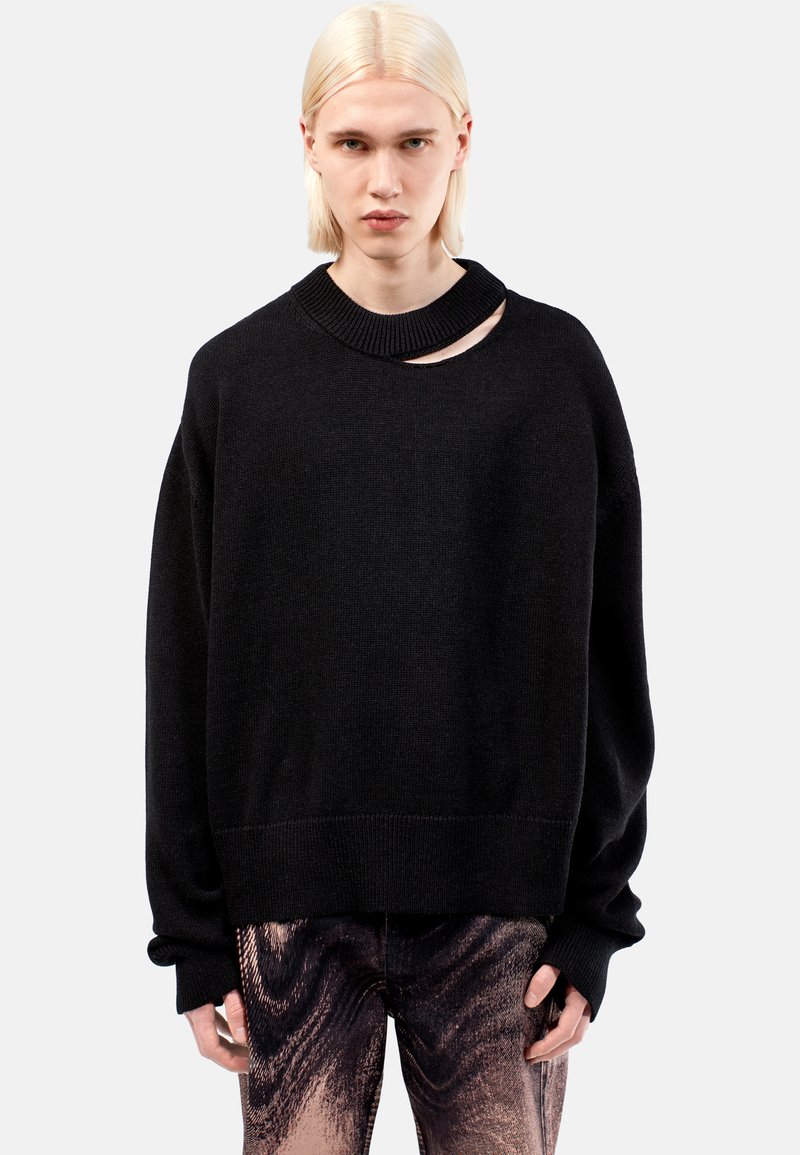 Svart oversized tröja med ribbad rundhalsning och en distinkt uttagsdetalj. Mjuk textur med sänkt axel och breda manschetter.