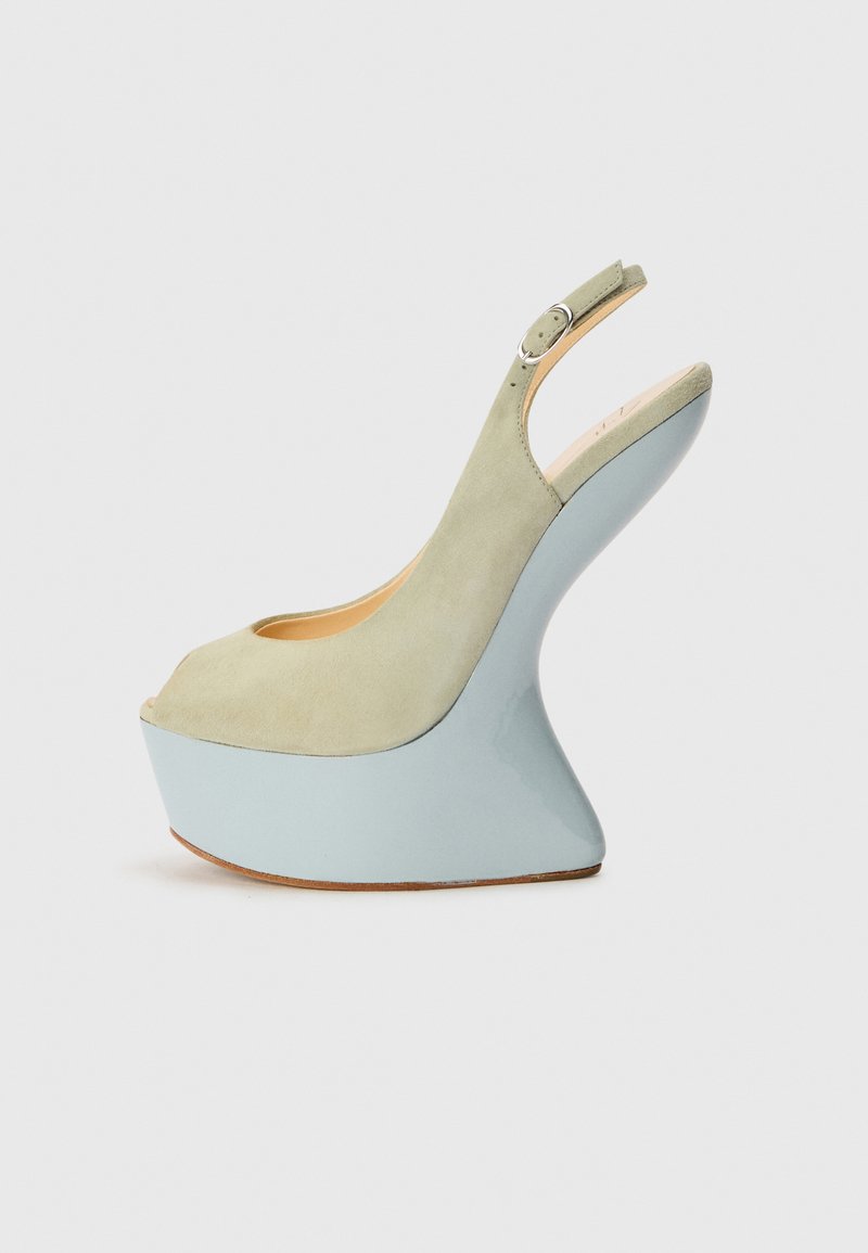 Hochhackiger Slingback-Schuh aus hellgrünem Wildleder mit einem Peeptoe-Design und einem glänzenden blauen Keilabsatz. Mit einem kreisförmigen Schnallen-Detail ausgestattet.
