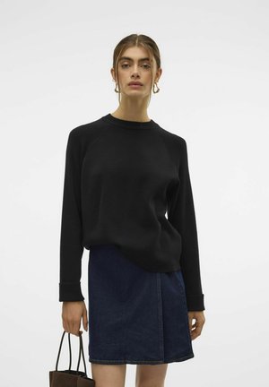Schwarzer Sweatshirt mit langen Ärmeln, geripptem Hals- und Bündchenabschluss, kombiniert mit einem dunklen Denim-Rock, der eine Frontnaht und dezente Nähte aufweist.