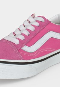 Ροζ πάνινο αθλητικό παπούτσι με λευκά κορδόνια, λευκή πλαϊνή λωρίδα και λευκή λαστιχένια σόλα με μαύρο περίγραμμα.