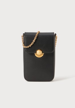 Black leather crossbody bag with a gold chain strap, circular gold hardware closure, and stitched edges. Compact rectangular shape.