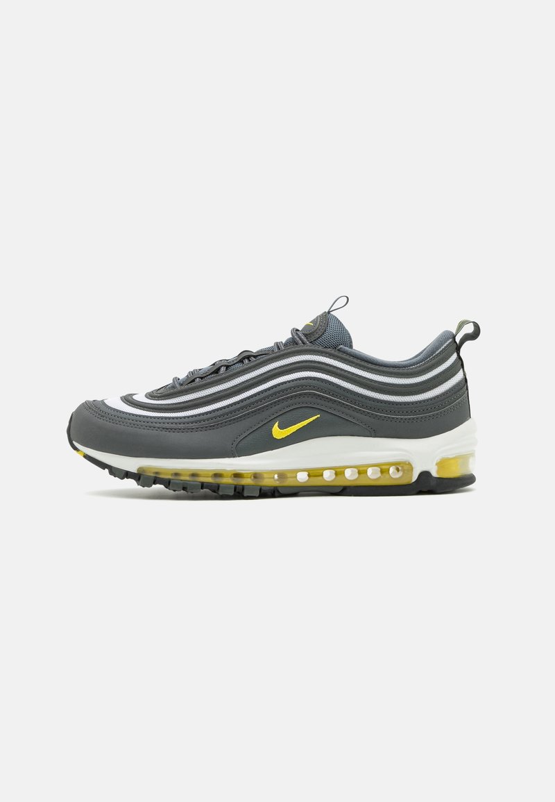 Baskets Nike Air Max 97 gris foncé avec des accents jaunes, semelle intermédiaire blanche et amorti visible à air sur un fond clair uni.