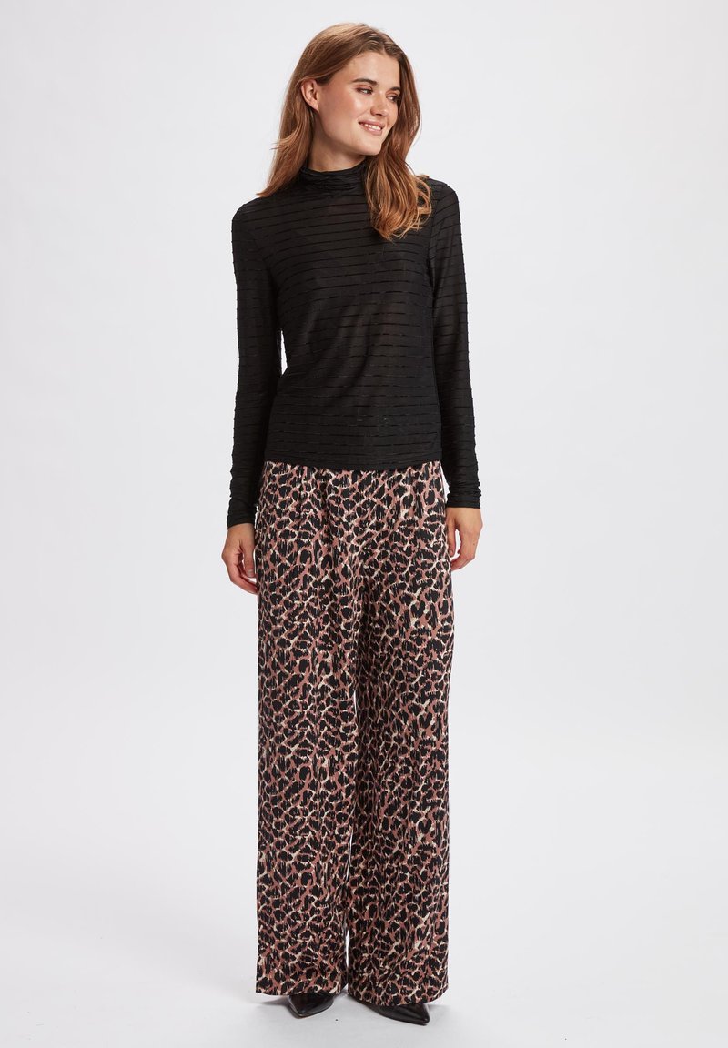 Schwarzes, gestreiftes Langarmoberteil kombiniert mit weit geschnittenen rosa und schwarzen Leopardenmuster-Hosen. Glatter Stoff, lockere Passform, elegantes Design.