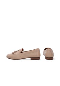 Beige Lederloafers mit runder Zehenform, dekorativen Quasten und einem niedrigen, braun gestapelten Absatz. Sichtbare Nähte betonen das Design.
