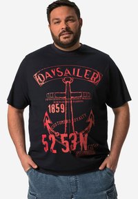 Svart bomullströja med stort röd grafiskt tryck av ett ankare och text, korta ärmar och en avslappnad passform. Marint tema.