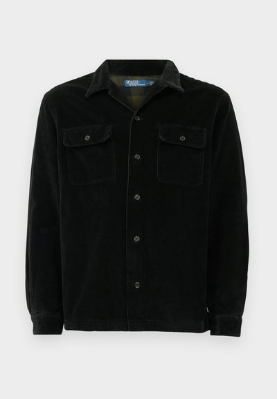 Black corduroy shirt with a classic collar, two chest pockets, button closure, and a ribbed texture. Long sleeves with button cuffs.