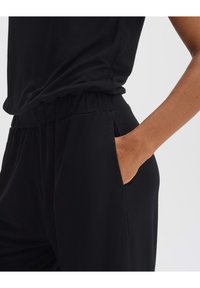 Schwarzes Kleidungsstück mit einem lockeren Schnitt, elastischem Bund, seitlichen Taschen und geschmeidiger, weicher Textur. Geeignet für Freizeitkleidung.