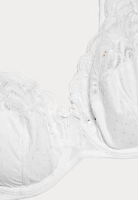 Vit behå med spetsdetaljer och prickigt mönster. Mjukt tyg med en strukturerad form och en fin rosett i mitten.