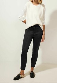 Musta räätälöityt housut slim-fit-leikkauksella, sivupainikiinnityksellä ja nappikiinnityksellä. Yhdistettynä kerma väriseen ribbiknitti topiin ja mustiin loafereihin.