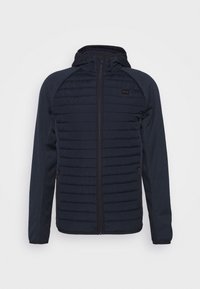 Marineblauwe gewatteerde jas met een ritssluitingen, capuchon en raglanmouwen. Bevat textuurpanelen en een klein logo op de linkerborst. Zachte stof.