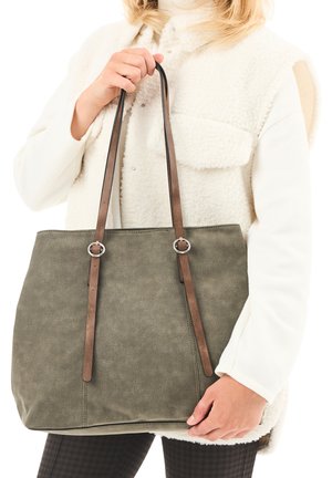 Green canvas tote bag with brown leather straps featuring silver rings. The bag has a rectangular shape and a smooth texture.