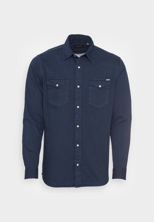 Camisa de manga longa azul-marinho com botão frontal, dois bolsos no peito e bainha arredondada. Feita de um tecido leve e texturizado.