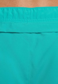 Calções de tecido turquesa com cinta de cintura plana. Textura suave, detalhes mínimos de costura e sem peças metálicas ou padrões visíveis.