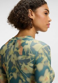 Floral print bodysuit in sheer fabric featuring soft pastel colors, fitted design, and a crew neckline with logo detail at the back.