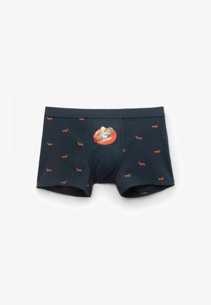 Marineblaue Boxershorts mit kleinen roten Dackelprints und einer zentralen Hundeillustration, die eine Bierkrug hält und auf einem aufblasbaren Ring entspannt.