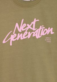 Olivgrön sweatshirt med stor rosa text som säger "Next Generation" och "ONLY SINCE 1995" i ett modernt skriptfont. Mjuk textur.