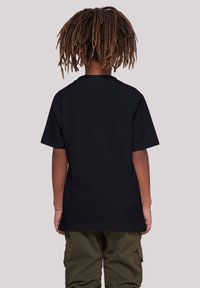 Camiseta negra de manga corta con cuello redondo, hecha de algodón, con una textura suave y un corte relajado, combinada con pantalones cargo en color oliva.