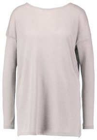 Haut ample à manches longues gris clair, en tissu tricoté texturé, col large, fentes latérales pour faciliter les mouvements, avec une silhouette décontractée.
