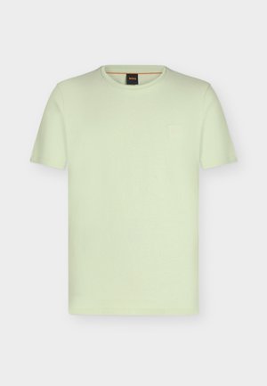 T-shirt vert clair à manches courtes et col rond, avec un petit logo embossé sur la poitrine gauche et une étiquette noire à l’intérieur du col.