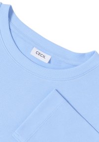 Lichtblauwe, geribbelde katoenen t-shirt met een ronde halslijn en korte mouwen. Het etiket zegt "CECIL." Gladde textuur met een aansluitend ontwerp.