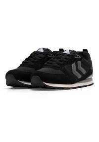 Scarpe da ginnastica nere con una tomaia in materiali misti che presenta rete e suede, progettate con una intersuola bianca e dettagli grigi sui lati.