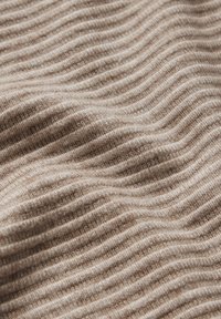 Tessuto a coste beige con una texture morbida, caratterizzato da strisce alternate in rilievo e in abbassamento. Il materiale appare accogliente e caldo.