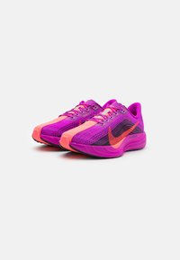 Et par livlige lilla og pink atletiske løbesko med orange accenter og Nike swoosh-logo vinklet på en hvid baggrund.