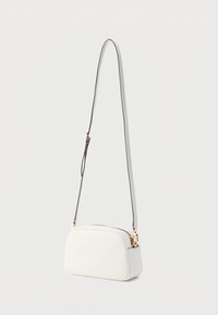 Valkoinen käsilaukku, jossa selkeälinjainen muoto, sileä pinta, säädettävä olkahihna ja kullanväriset metalliosat. Yläosassa vetoketjullinen suljenta.