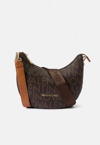Kabelka Valentino z hnědého materiálu s vyraženým logem, zakřiveným tvarem, zlatým kováním a kontrastním opásáním přes rameno v odstínu tan.