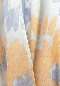 Tissu léger arborant un motif floral dans des tons doux d'orange et de bleu pâle sur un fond texturé et transparent.